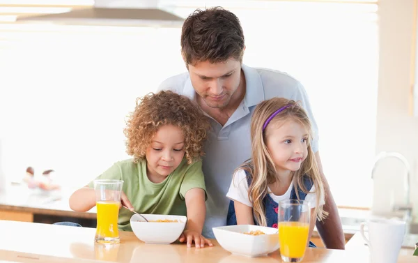 Jovem pai com seus filhos tomando café da manhã — Fotografia de Stock