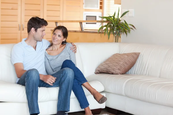 Smiling couple sitting on a couch — Stock Photo, Image