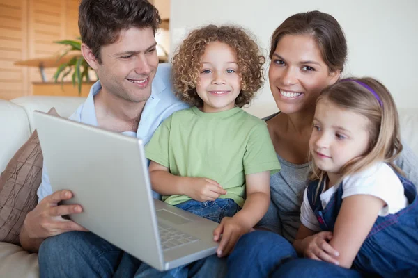 Familia sonriente usando un portátil — Foto de Stock