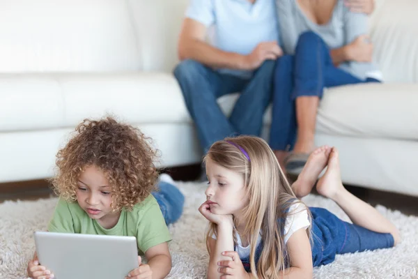 Παιδιών που χρησιμοποιούν έναν υπολογιστή δισκίο, ενώ βλέποντας τους γονείς — Φωτογραφία Αρχείου