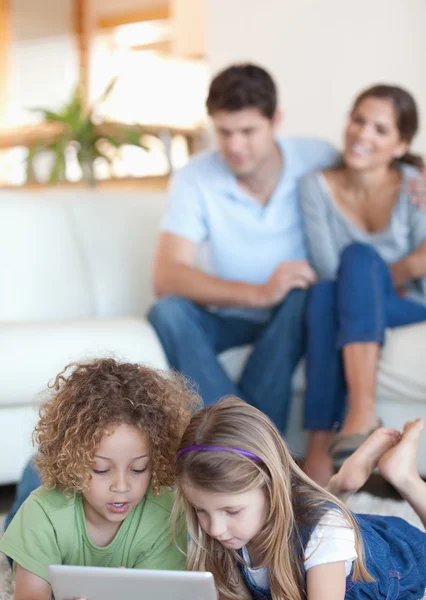 Portrait of children using a tablet computer while their parents — Stock Photo, Image