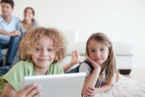 Niños felices usando una tableta mientras sus padres felices — Foto de Stock