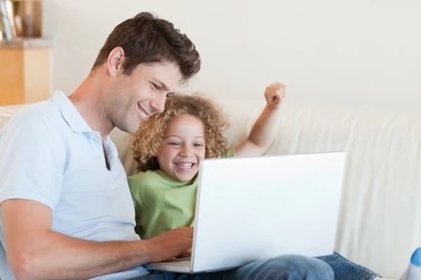 Alegre niño y su padre usando un ordenador portátil — Foto de Stock
