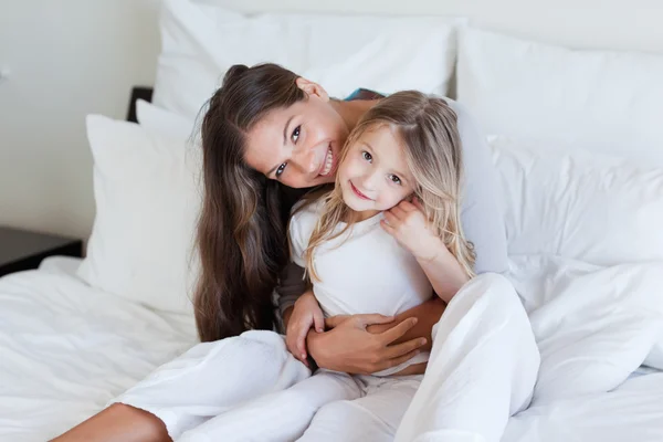 Mor och hennes dotter poserar på en säng — Stockfoto
