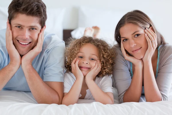 Parents lying on a bed with their son — Stock Photo, Image