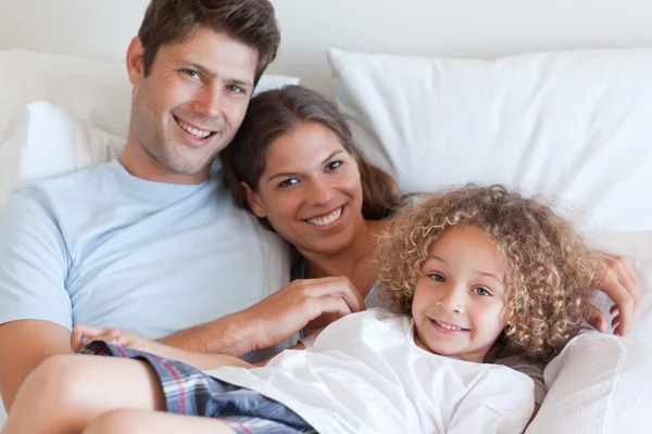 Famiglia sorridente che si rilassa su un letto — Foto Stock