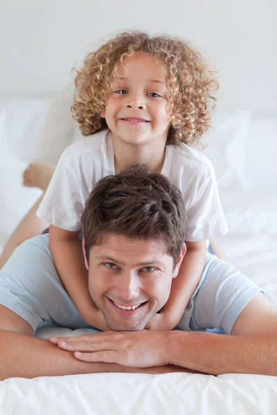 Улыбающиеся отец и ребенок лежат на кровати — стоковое фото