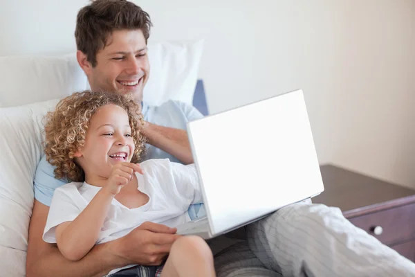 父亲和孩子在床上使用笔记本电脑 — 图库照片