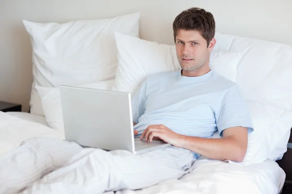 男子躺在床上用的笔记本电脑 — 图库照片