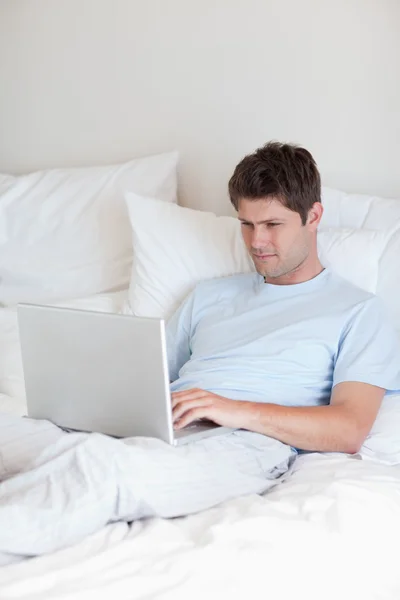 Man surfing the internet in bed — Stock Photo, Image