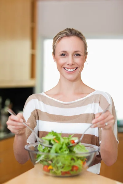 Mulher sorridente mexendo salada — Fotografia de Stock