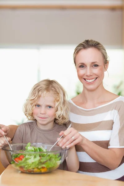 Smiling mother and son stirring salad — Stockfoto