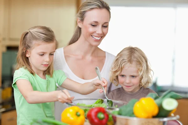 Anne ile kızı ve oğlu salata hazırlık — Stok fotoğraf