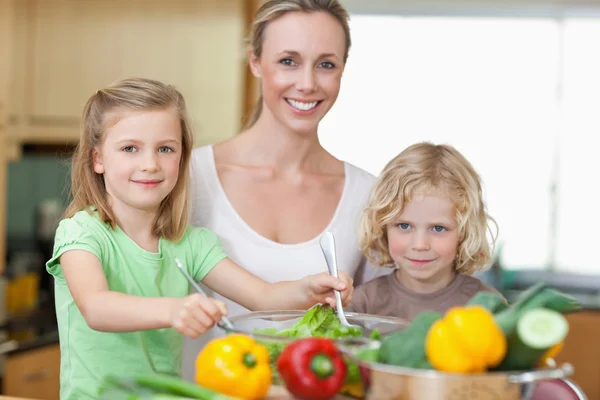 Женщина со своими детьми готовит салат — стоковое фото