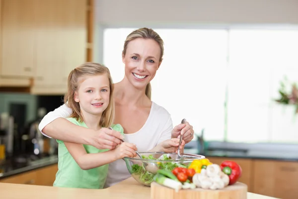 Lächelnde Mutter und Tochter rühren Salat — Stockfoto