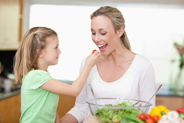 Girl feeding her mother with tomato — Stock Photo, Image