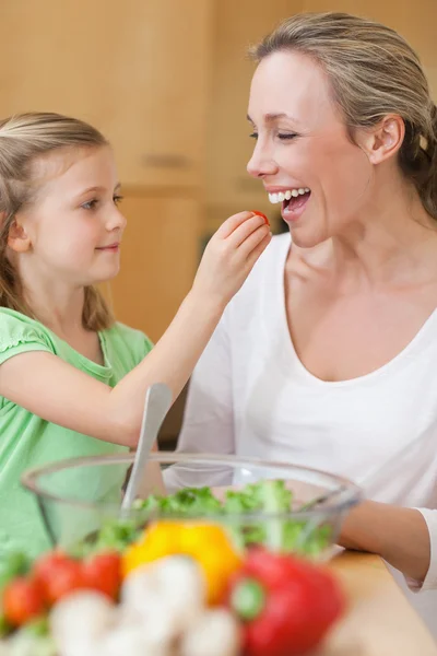 Menina alimentando sua mãe com salada — Fotografia de Stock