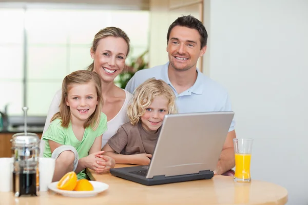 Lachende familie via het internet in de keuken — Stockfoto