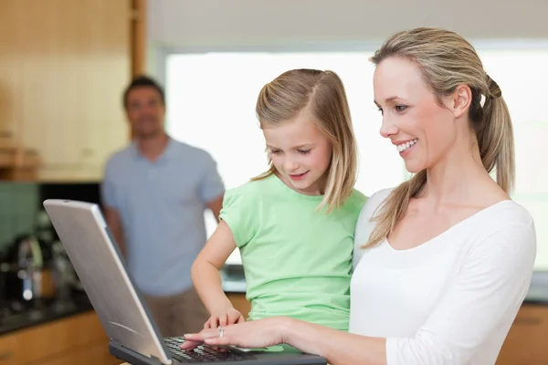 Happy mother and daughter surfing the web with father in the bac — Stock Photo, Image