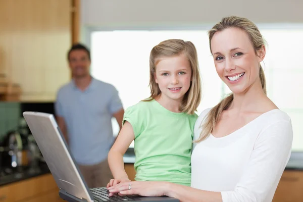 Matka i córka za pomocą laptopa z ojcem, w tle — Zdjęcie stockowe