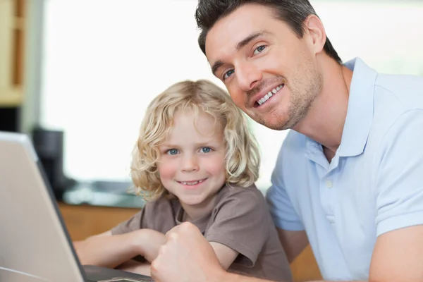 Leende far och son med bärbar dator — Stockfoto
