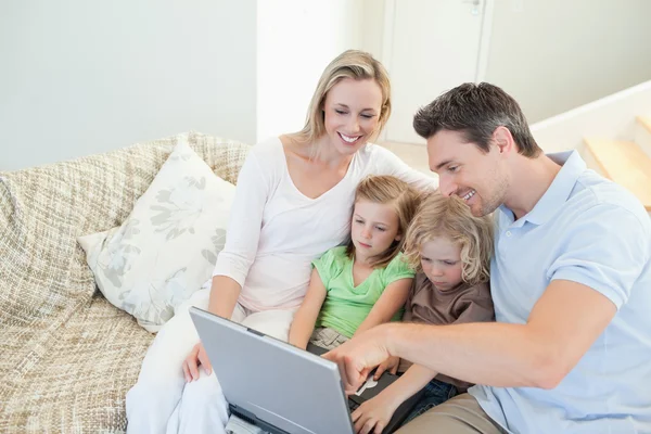 Семья на диване с ноутбуком — стоковое фото