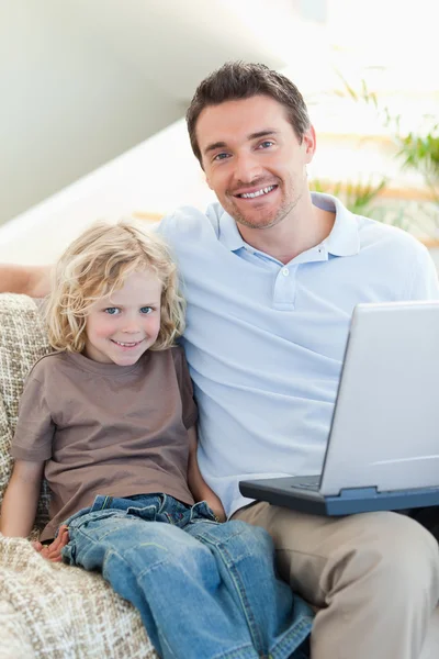 父亲和儿子在沙发用的笔记本电脑上 — 图库照片