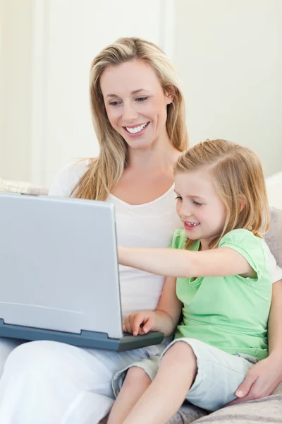 Mother and daughter with laptop on couch — Stock Photo, Image