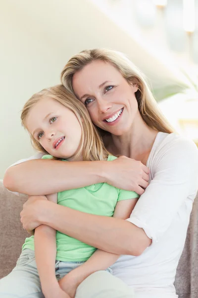 Madre che abbraccia la figlia sul divano — Foto Stock