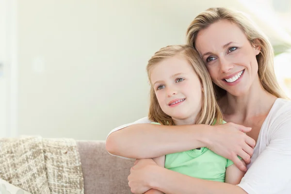 Mutter umarmt Tochter auf Couch — Stockfoto