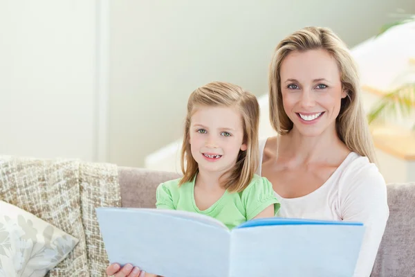 Mother and daughter reading a magazine on the sofa — Stock Photo, Image
