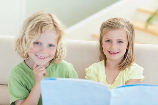 Siblings on the couch reading magazine — Stock Photo, Image