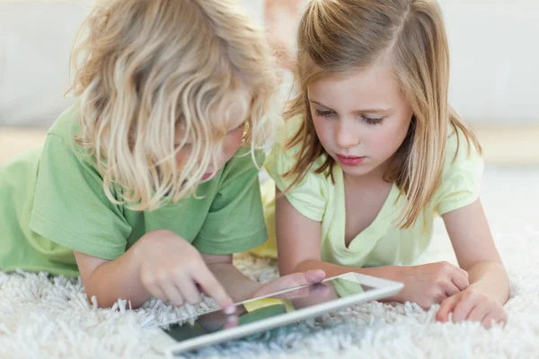 Siblings on the floor using tablet — Stock Photo, Image