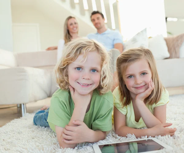 Дети на ковре с табличкой и родителями за ними — стоковое фото
