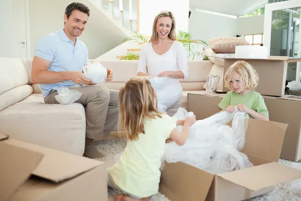 Família desembalagem caixa de papelão na sala de estar — Fotografia de Stock