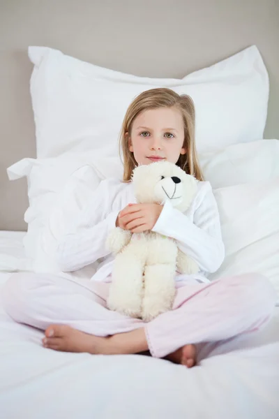 Dívka, objímala ji teddy na postel — Stock fotografie