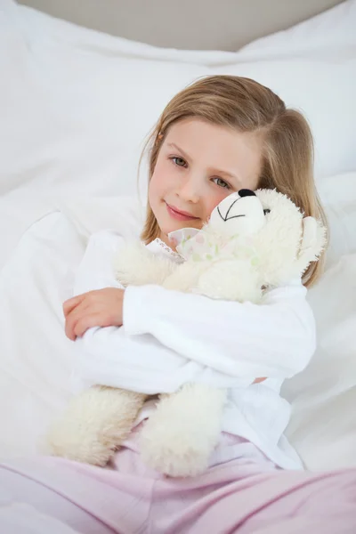 Meisje omarmen haar teddy op het bed — Stockfoto