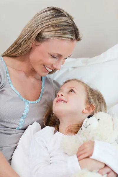 Мать обнимает свою дочь на кровати — стоковое фото