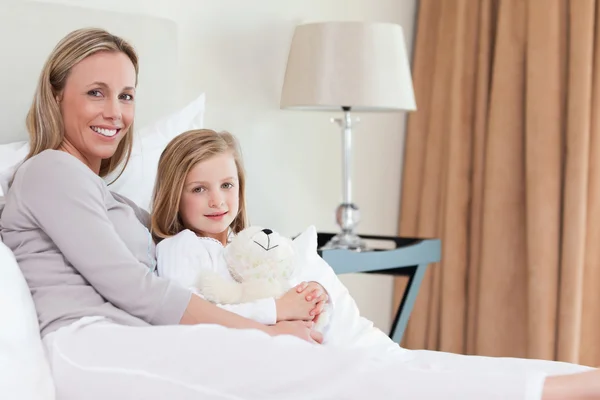Sidovy av mor och dotter sitter på sängen — Stockfoto