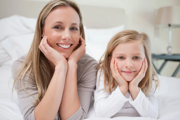 Smiling mother and daughter lying on the bed — Stock Photo, Image