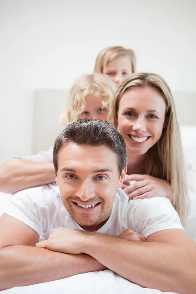 Smiling family lying on bed — Stock Photo, Image
