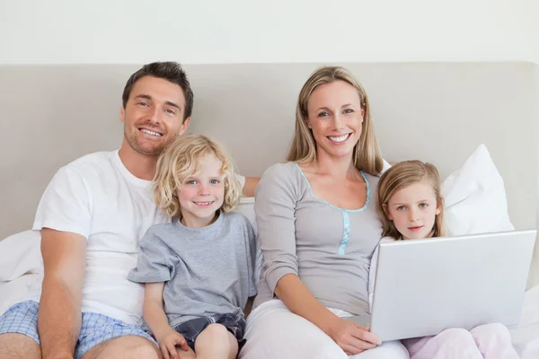 Familia sentada en la cama con portátil — Foto de Stock