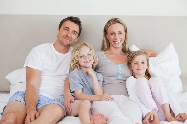 Familia sonriente sentada en la cama —  Fotos de Stock