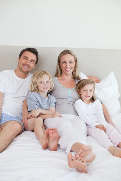 Yatakta oturmuş mutlu bir aile — Stok fotoğraf
