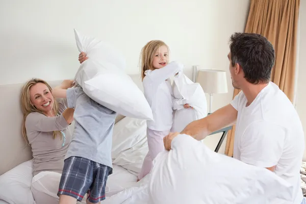 Familia juguetona teniendo una pelea de almohadas en el dormitorio — Foto de Stock