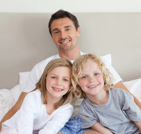 Vater sitzt mit seinen Kindern im Bett — Stockfoto
