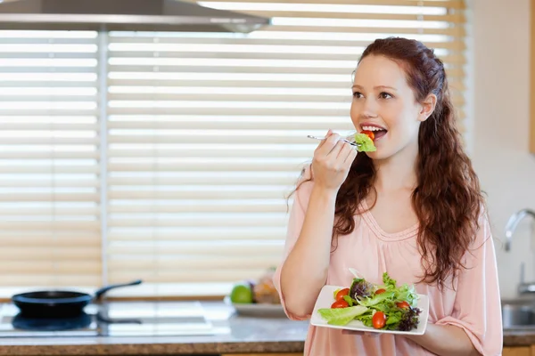 台所でいくつかのサラダを食べる少女 — ストック写真