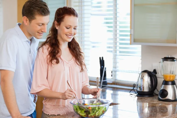 Pár s miskou salátu v kuchyni — Stock fotografie