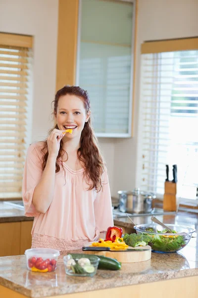 Žena okusování papriky při přípravě zdravý salát — Stock fotografie