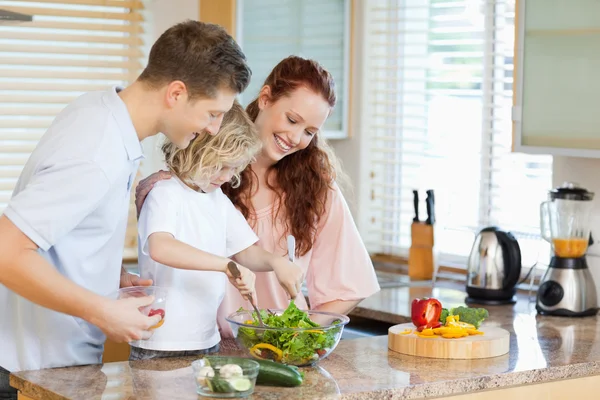Пара, позволяющая своему ребенку перемешивать салат — стоковое фото